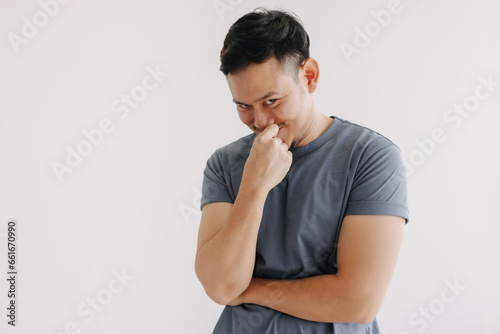 Evil looks of asian man in blue t-shirt smile and smirk stand isolated on white. photo