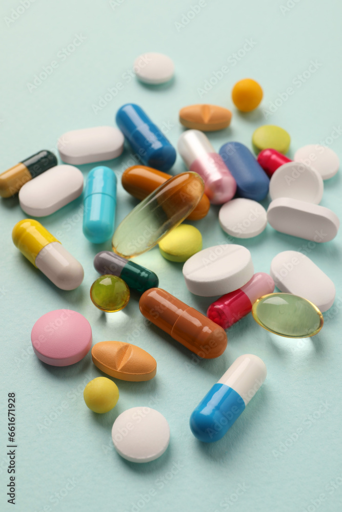 Pile of different pills on mint background, selective focus
