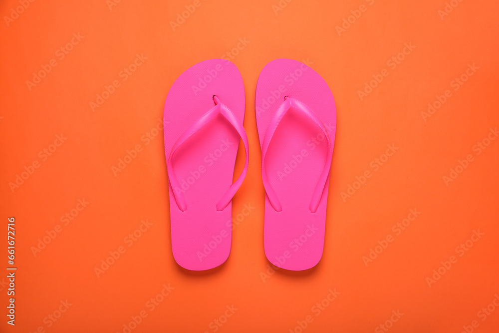Stylish pink flip flops on orange background, top view Stylish pink flip flops on orange background, top view