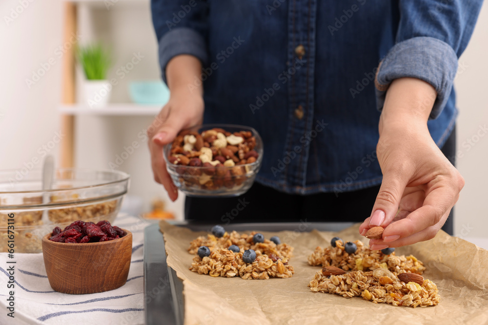 Making granola bars. Woman with nuts at table in kitchen, closeup