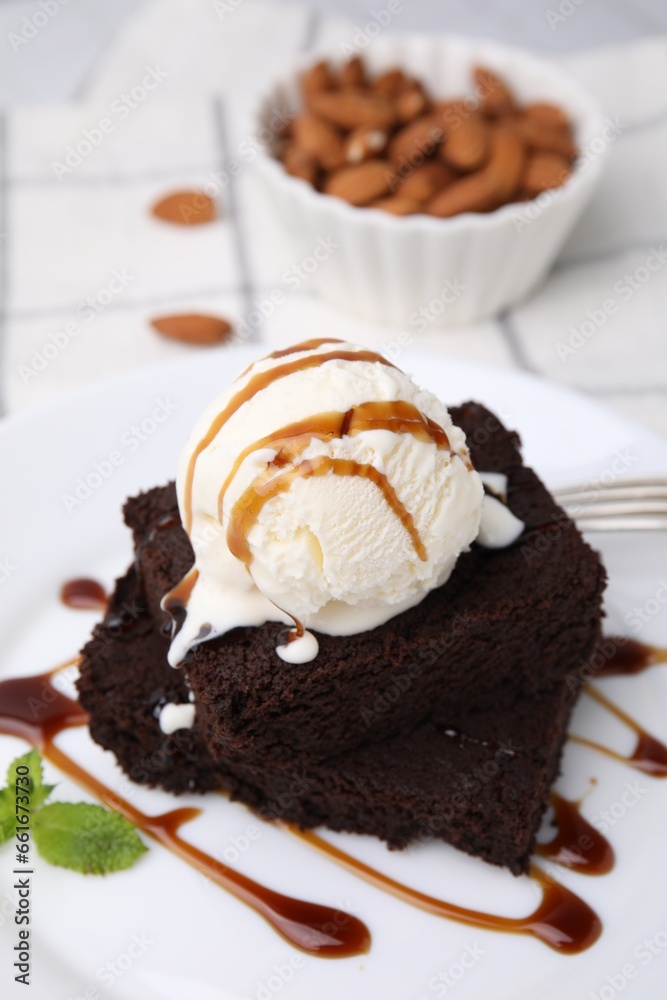 Tasty brownies served with ice cream and caramel sauce on table, closeup Tasty brownies served with ice cream and caramel sauce on table, closeup