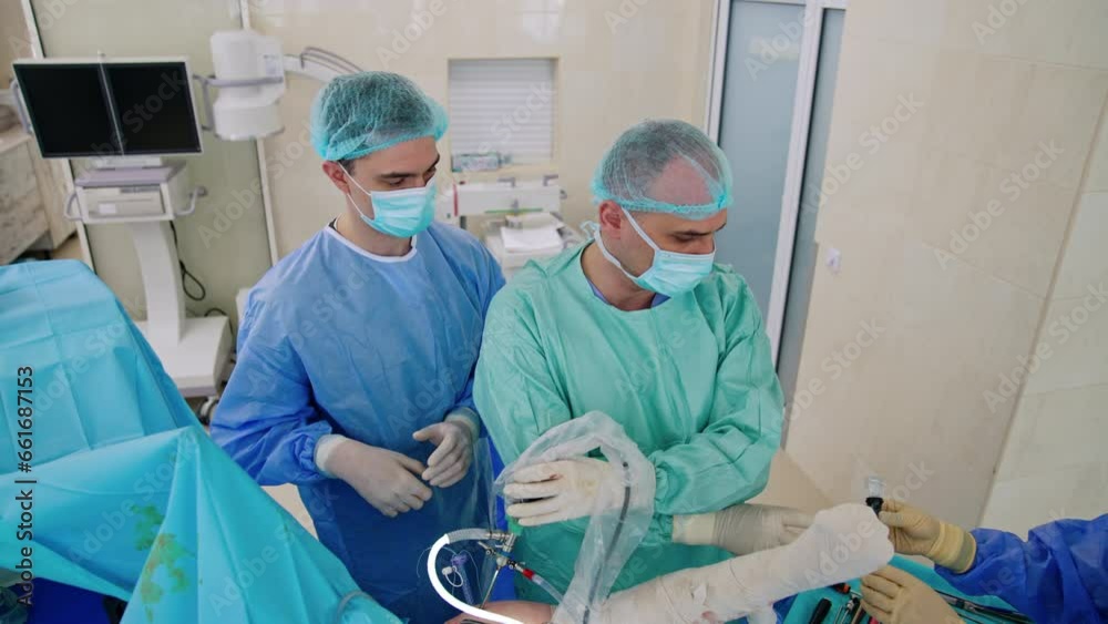 Young male doctors carry out laparoscopic operation using modern surgical devices. Nurse passes the tools to the surgeons. Top view. Young male doctors carry out laparoscopic operation using modern surgical devices. Nurse passes the tools to the surgeons. Top view.