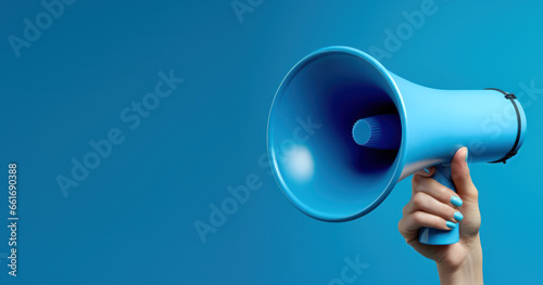 Woman confidently wielding a megaphone, set against a striking blue canvas © Malika