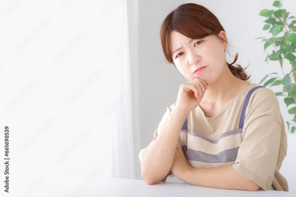 頬杖をついて考え事をするエプロン姿の女性 頬杖をついて考え事をするエプロン姿の女性