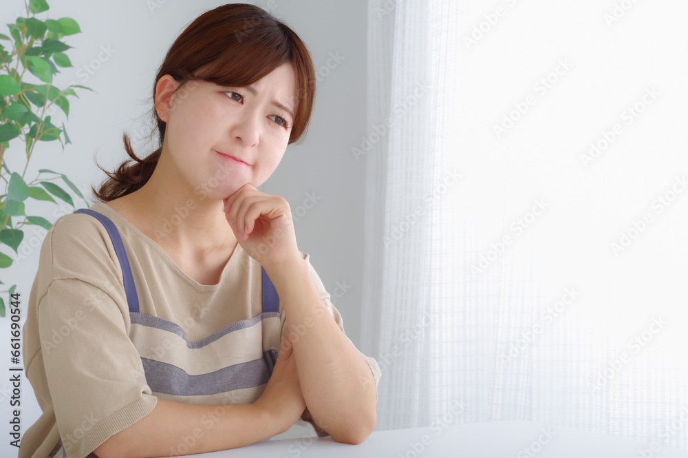 頬杖をついて考え事をするエプロン姿の女性 頬杖をついて考え事をするエプロン姿の女性