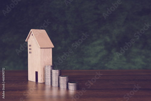 Coins stack in graph shape with wooden house for real estate or money savings planning and bank home loan or financial investment insurance.