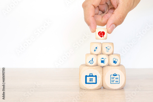 Hand chooses medical health care on cube wooden block stack pyramid concept of safety insurance for sick illness wellbeing protection plan or retirement healthy therapy treatment or health checkup