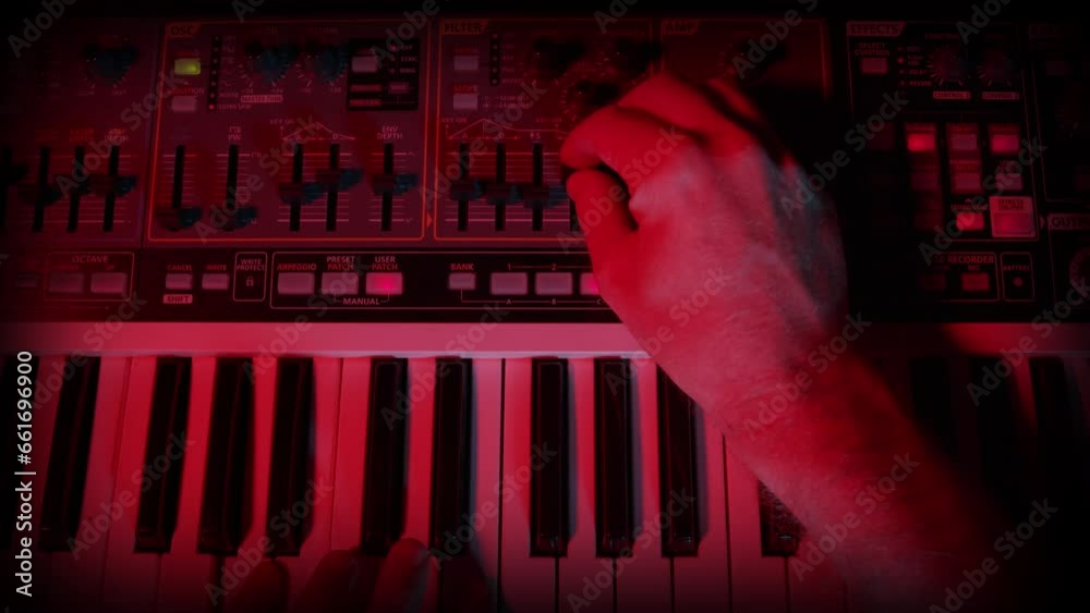 Synthesizer Musical Instrument Close Up, with Hand Tweaking, Adjusting  Buttons and Knobs. A moody lit modern, analogue synthesizer with the user adjusting the parameters of the sound.