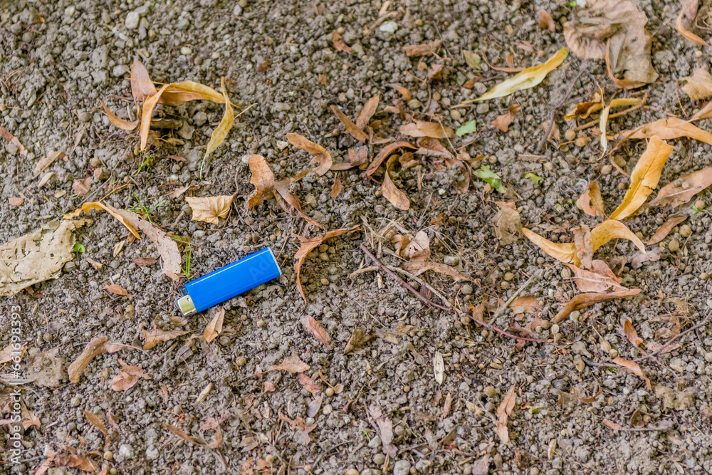Fototapeta premium Blue disposable cigarette lighter laying on ground.