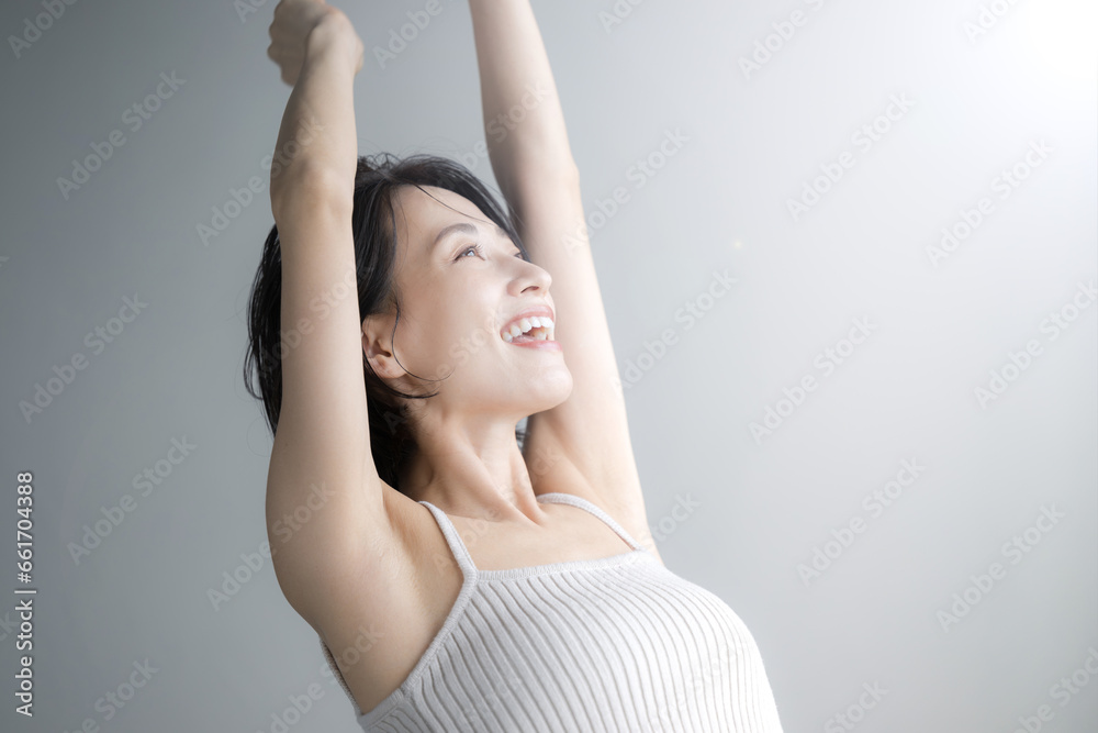 朝日の中腕を伸ばしてストレッチをする女性のクローズアップ　右にコピースペースあり