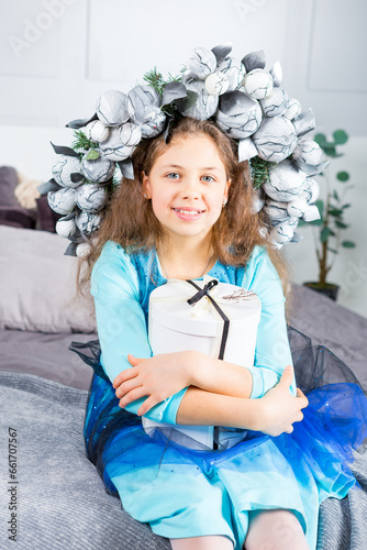 cheerful lass wearing beautiful gown is sitting on a wide bed in bedroom with xmas handsel in her hands photo