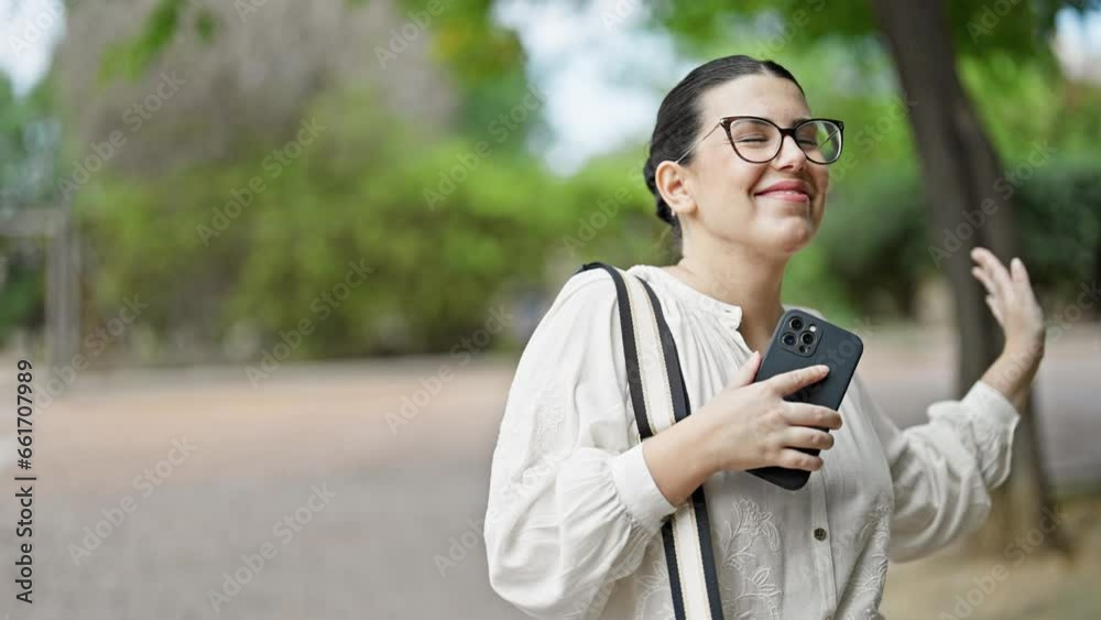 Young beautiful hispanic woman dancing using smartphone at the park Young beautiful hispanic woman dancing using smartphone at the park