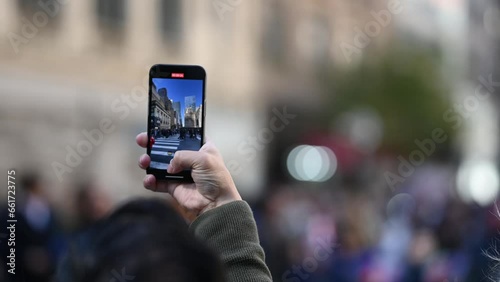 A person holding a phone and recordin a parade in new york city streets for columbus day. photo