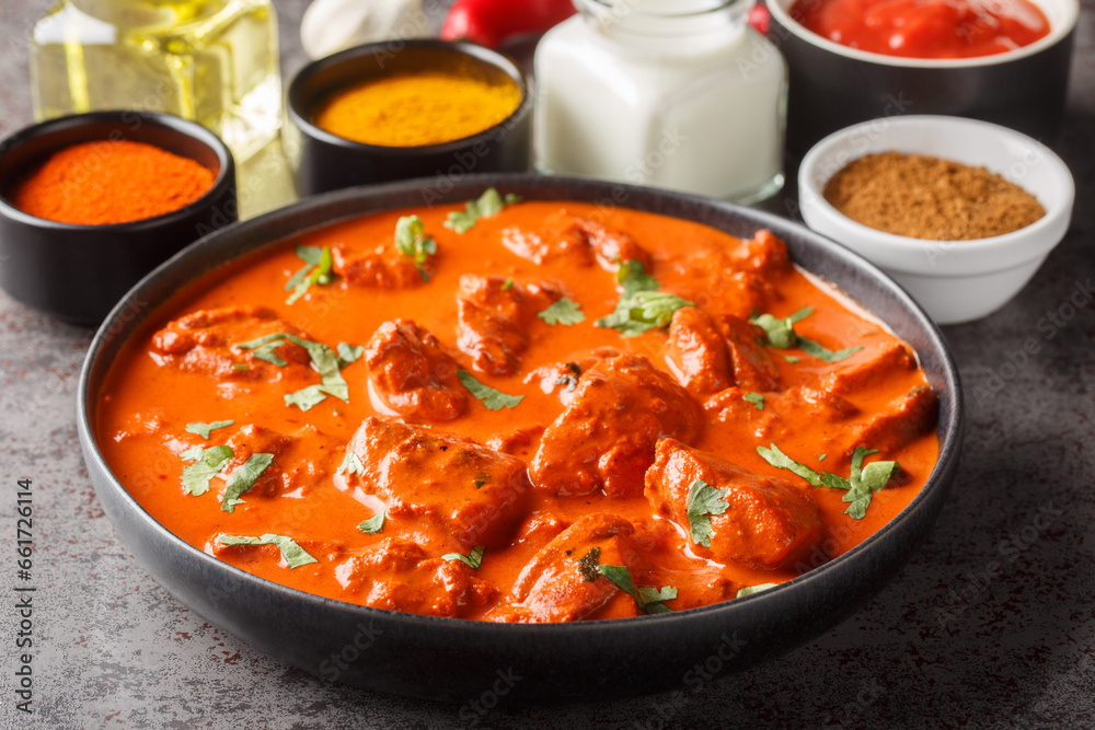 Delicious creamy chicken tikka masala surrounded by ingredients close-up in a bowl on the table. horizontal Delicious creamy chicken tikka masala surrounded by ingredients close-up in a bowl on the table. horizontal