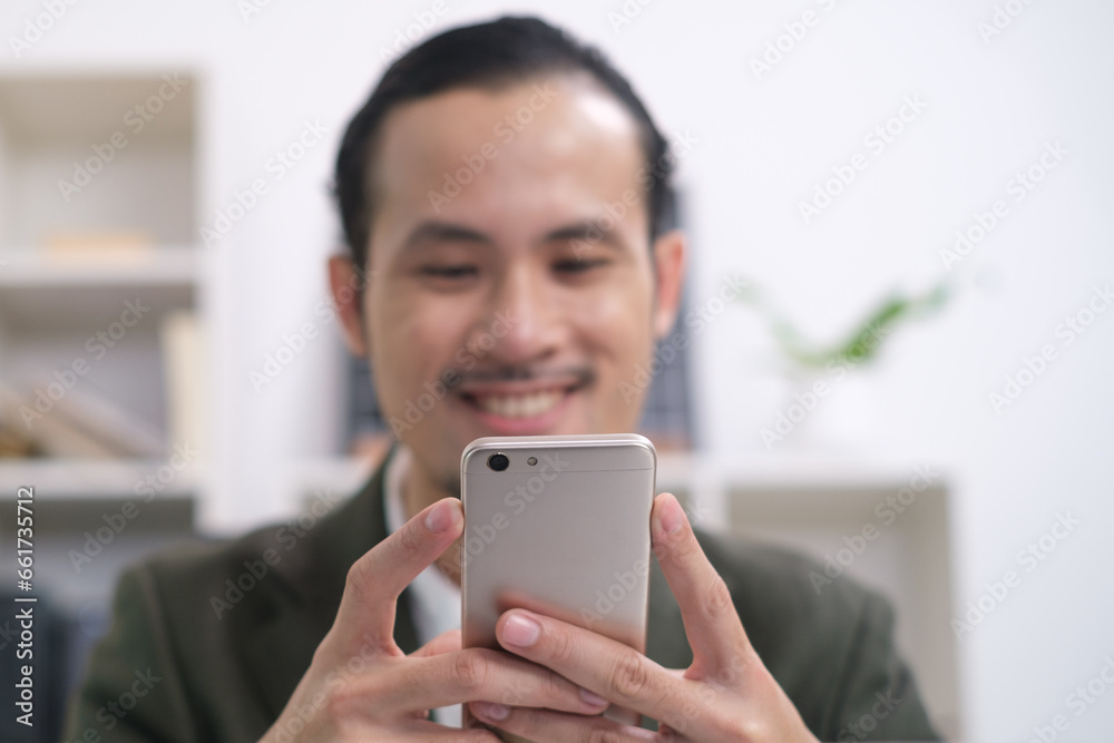 Close up of happy smile businessman holding smartphone in office for online chat message communication. Using mobile phone in workplace electronic transactions, shopping online. Focus at mobilephone. Close up of happy smile businessman holding smartphone in office for online chat message communication. Using mobile phone in workplace electronic transactions, shopping online. Focus at mobilephone.