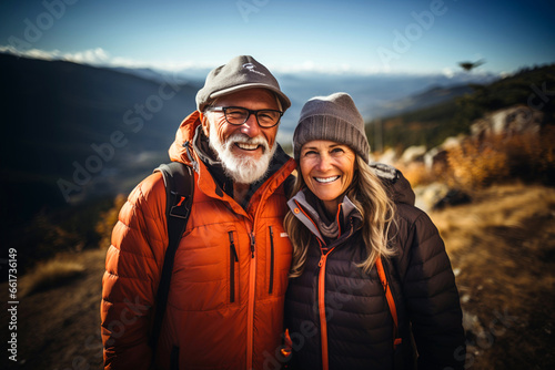 Active sport elderly healthy lifestyle concept. Excited portrait of senior active smiling mature couple hiking trekking in sunglasses look happy on top of mountains winter day time, happily retired