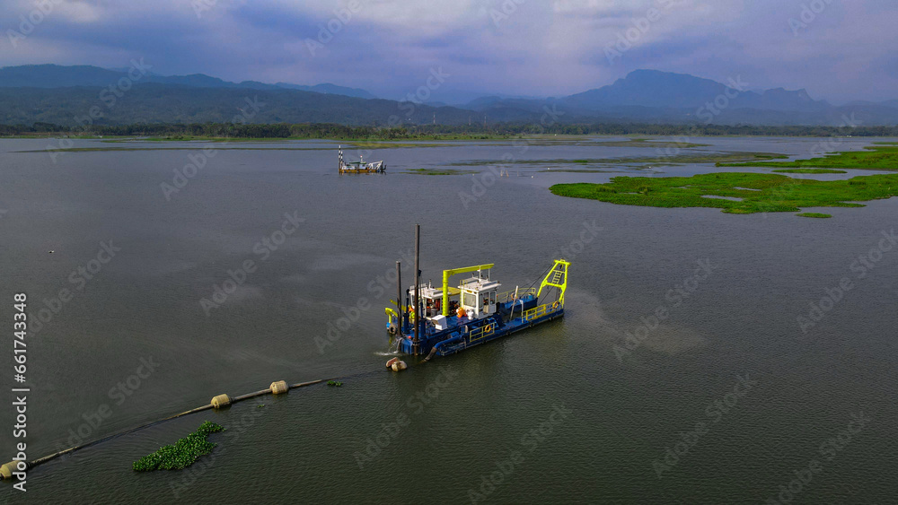 Aerial documentary of mud cleaning vessel in the lake from above cleaning the reservoir