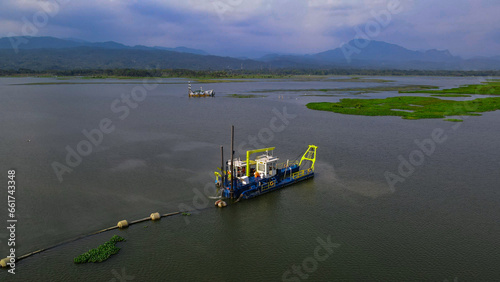 Aerial documentary of mud cleaning vessel in the lake from above cleaning the reservoir