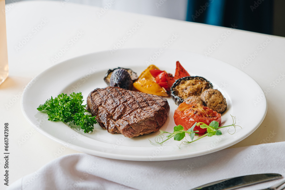 beef steak with grilled vegetables and herbs on a light background beef steak with grilled vegetables and herbs on a light background