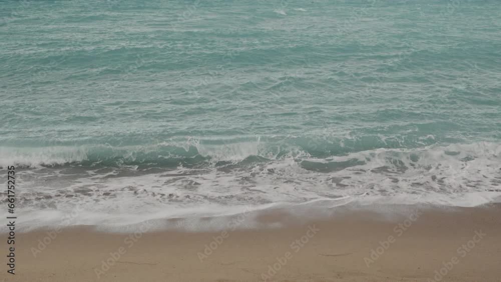 Slow motion clear blue waves with strong wind on a sandy empty beach in Cannes in spring Slow motion clear blue waves with strong wind on a sandy empty beach in Cannes in spring