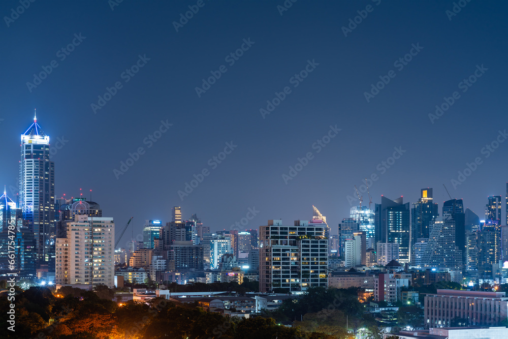 Night Bangkok panoramic city view, green trees and skyscrapers. Copy space