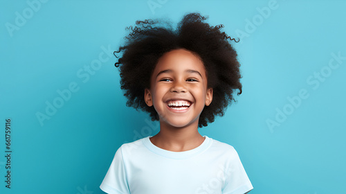 Close-up of a smiling African American little girl with white perfect teeth, isolated on a blue studio background with copy space. Children's Dental Care. Dentistry concept.