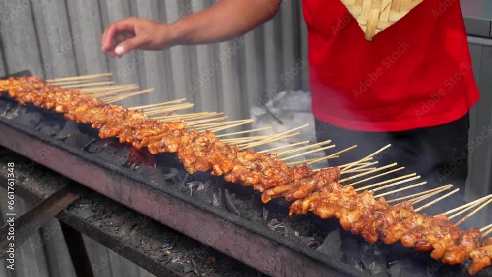 a man hand is grilling chicken satay