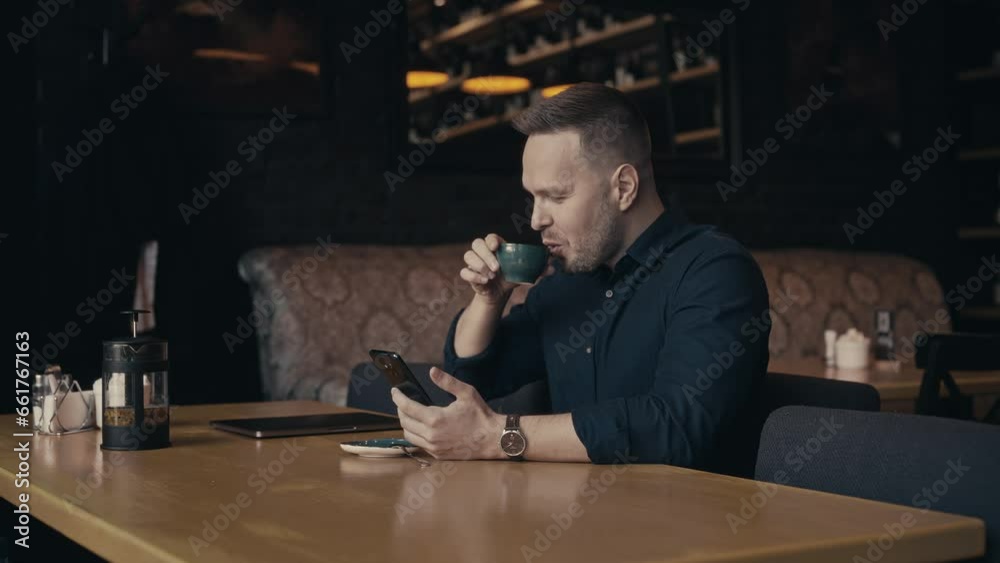 A man sits in a stylish cafe and uses a smartphone. Constant communication is possible thanks to the Internet. A man sits in a stylish cafe and uses a smartphone. Constant communication is possible thanks to the Internet.