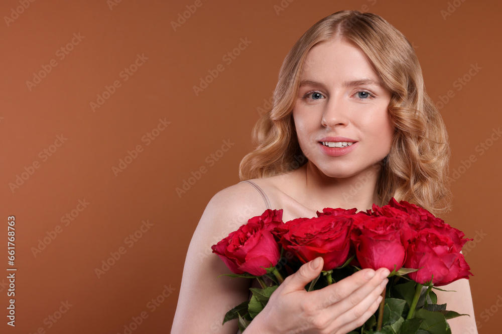 Beautiful woman with blonde hair holding bouquet of red roses on brown background. Space for text Beautiful woman with blonde hair holding bouquet of red roses on brown background. Space for text