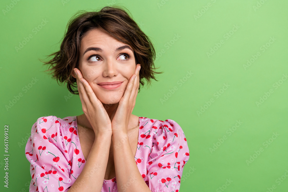Photo portrait of pretty young girl touch cheeks look empty space wear trendy pink cherry print outfit isolated on green color background Photo portrait of pretty young girl touch cheeks look empty space wear trendy pink cherry print outfit isolated on green color background