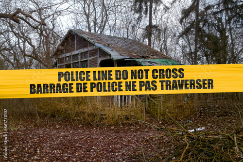 Bilingual Canadian police tape barricading an abandoned cabin in the wood