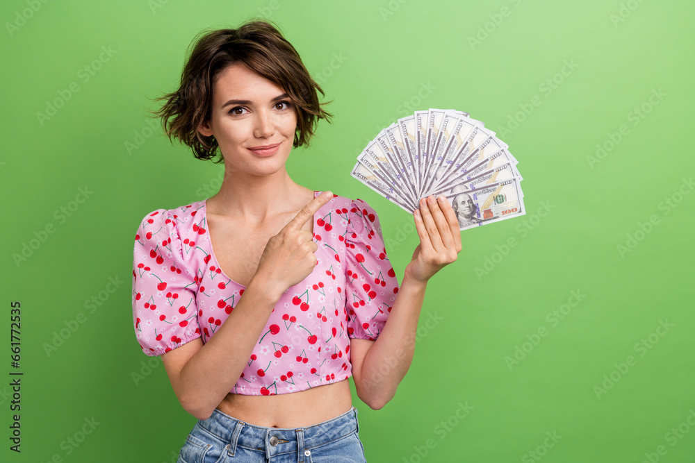 Photo of attractive young woman point banknotes money fan dressed stylish pink cherry print clothes isolated on green color background Photo of attractive young woman point banknotes money fan dressed stylish pink cherry print clothes isolated on green color background