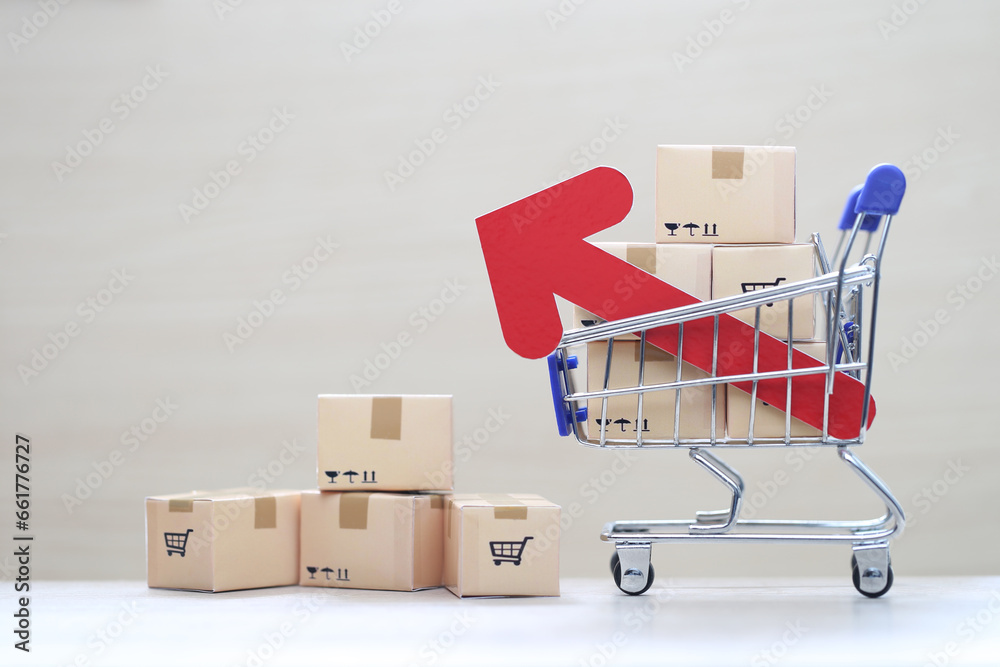 Global inflation or Deflation concept, Red arrow graph and brown parcel box on model miniature shopping cart on wooder background,Hyperinflation