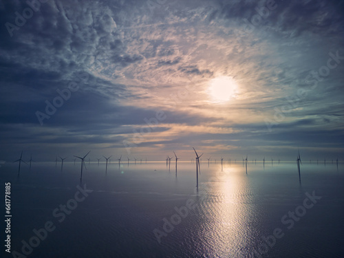 Birds eye view of the wind turbine producing green energy. Fryslan wind farm drone view - windmill farm in the Netherlands during the sunrise producing renewable energy. photo