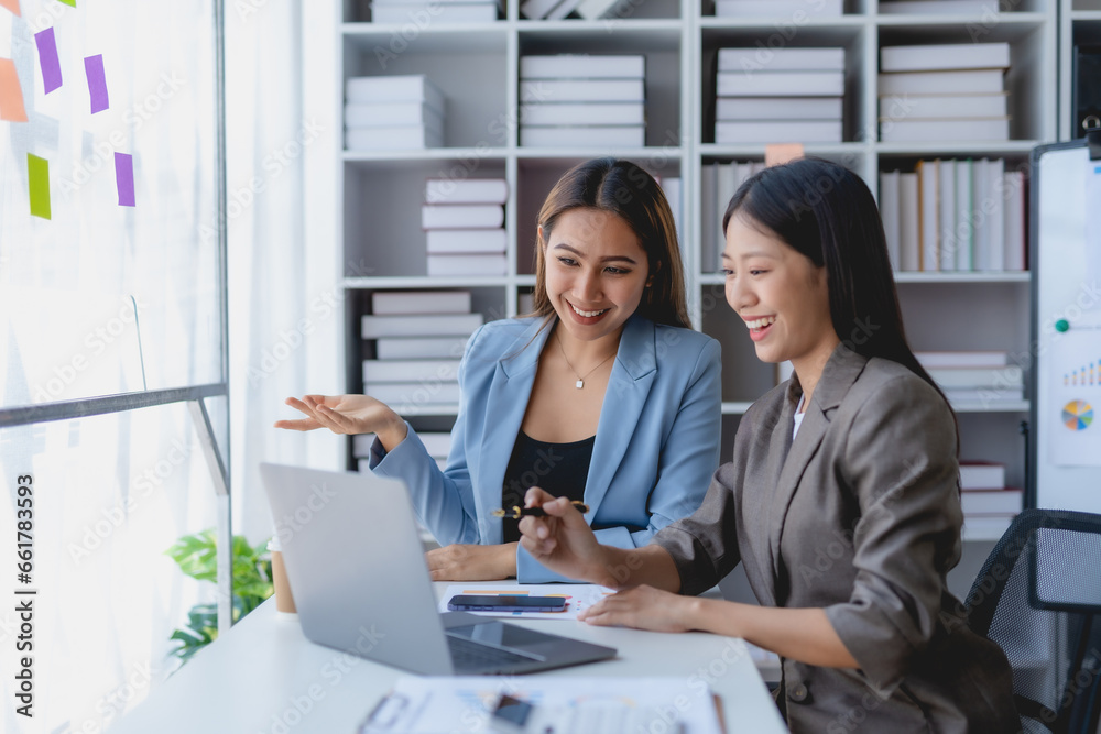 Two Asian businesswoman teamwork discussing and using laptop. Two Asian business women are talking and consulting. Two Asian businesswoman teamwork discussing and using laptop. Two Asian business women are talking and consulting.