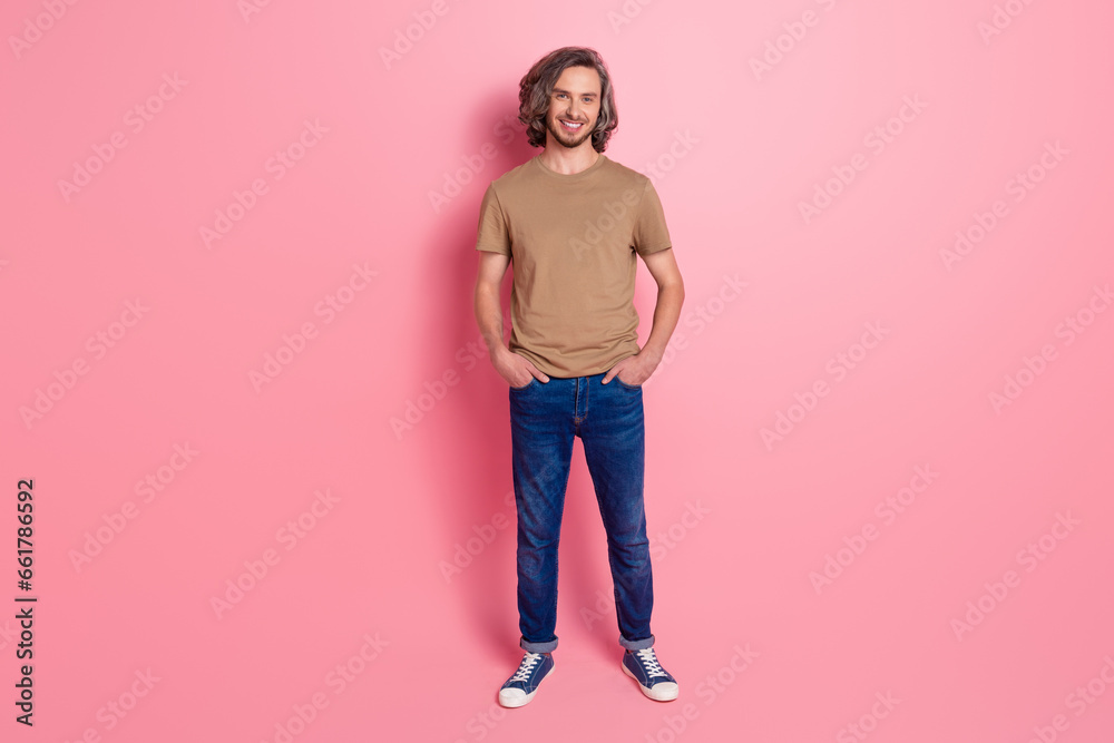 Full length photo of good mood guy with long haircut wear stylish t-shirt hold arms in pockets isolated on violet color background Full length photo of good mood guy with long haircut wear stylish t-shirt hold arms in pockets isolated on violet color background