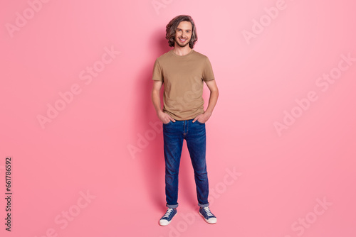 Full length photo of good mood guy with long haircut wear stylish t-shirt hold arms in pockets isolated on violet color background