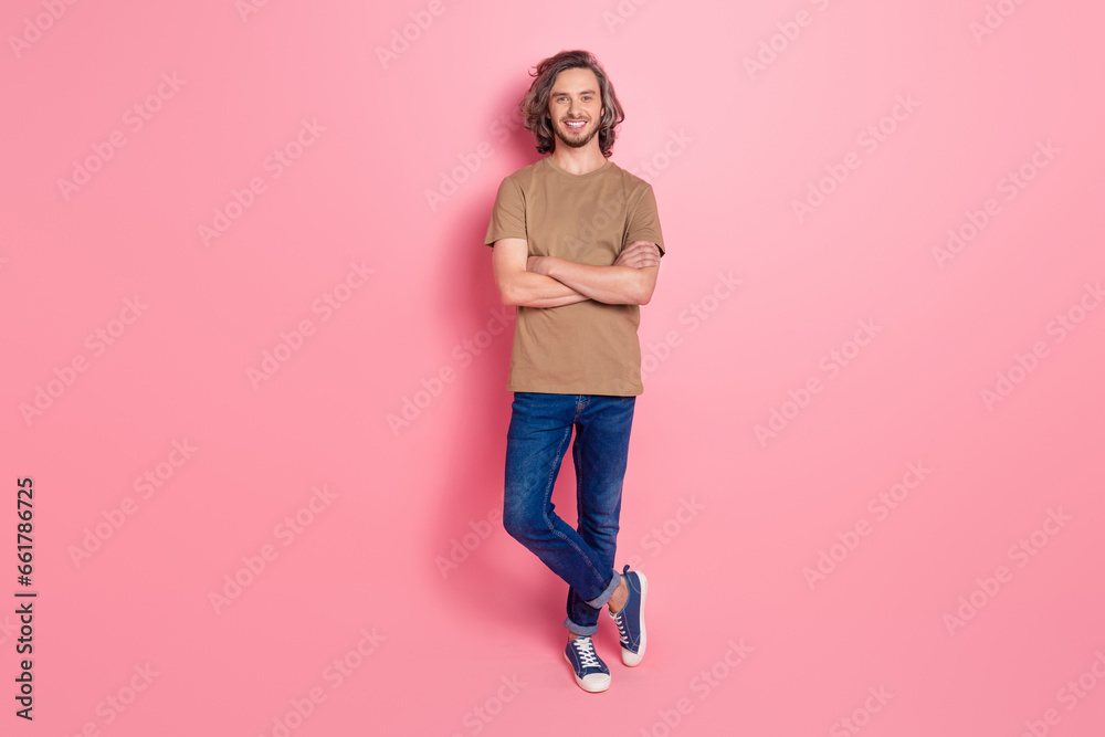 Full size photo of cool optimistic man with long hairstyle dressed beige t-shirt standing arms crossed isolated on pink color background Full size photo of cool optimistic man with long hairstyle dressed beige t-shirt standing arms crossed isolated on pink color background
