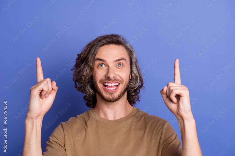 Photo of crazy positive man with long hairstyle dressed beige t-shirt directing look empty space sale isolated on purple color background Photo of crazy positive man with long hairstyle dressed beige t-shirt directing look empty space sale isolated on purple color background