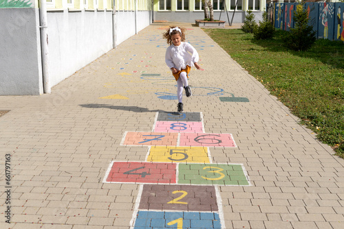 Junior schoolgirl playing hopscotch in school yard