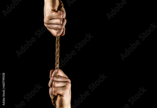 Hand holding a rope, climbing rope, strength and determination. Strong hold. Two hands, helping hand of a friend. Rescue, help, helping gesture or hands. Conflict tug of war. Rope, cord
