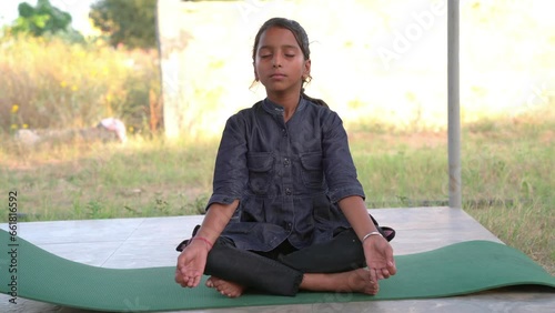 Indian Girl performing Yoga asana or meditation or dhyan, sitting on youga mat photo