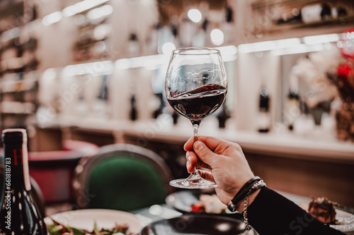 man hand holding a glass with red wine in a restaurant