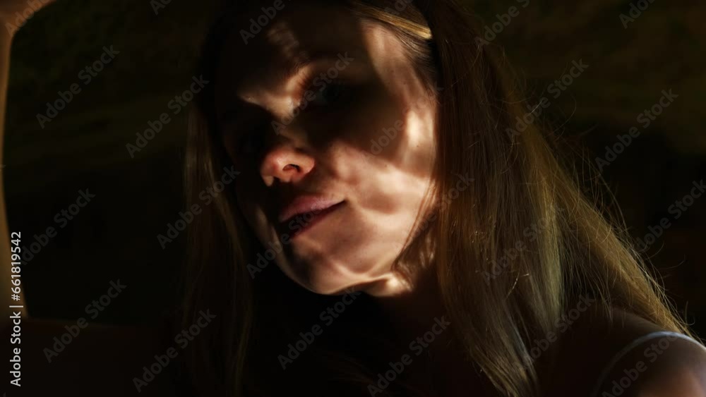girl's face in shadows and reflection of water in a cave near a stone. the girl touches the walls of a dark cave girl's face in shadows and reflection of water in a cave near a stone. the girl touches the walls of a dark cave
