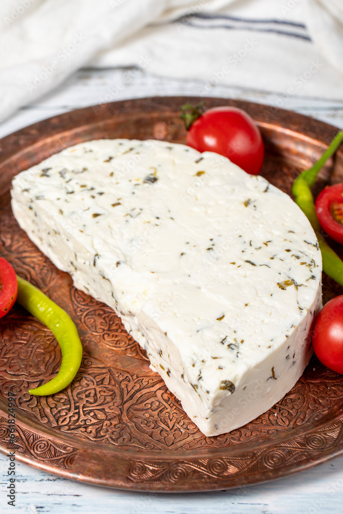 Herb cheese on a copper plate. Slices of herbed cheese on wooden background. local name otlu peynir. Close up