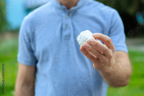 A man's hand holds a marshmallow, snack and fast food concept. Selective focus on hands with blurred background