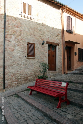 Italy, Marche: Red bench in the street.