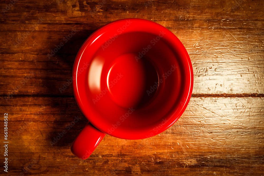 Red porcelain tea cup on a wooden kitchen table.