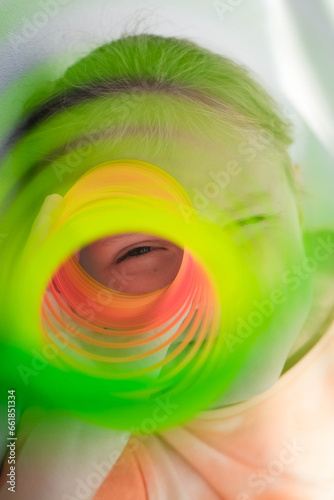 Foto The child's eye looks through the orange-green dense, colorful flexible children's toy, fun plastic toy