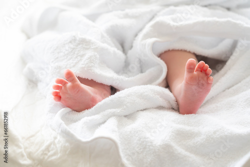 Tiny newborn feet gently emerge from a towel. Concept of post-bath serenity